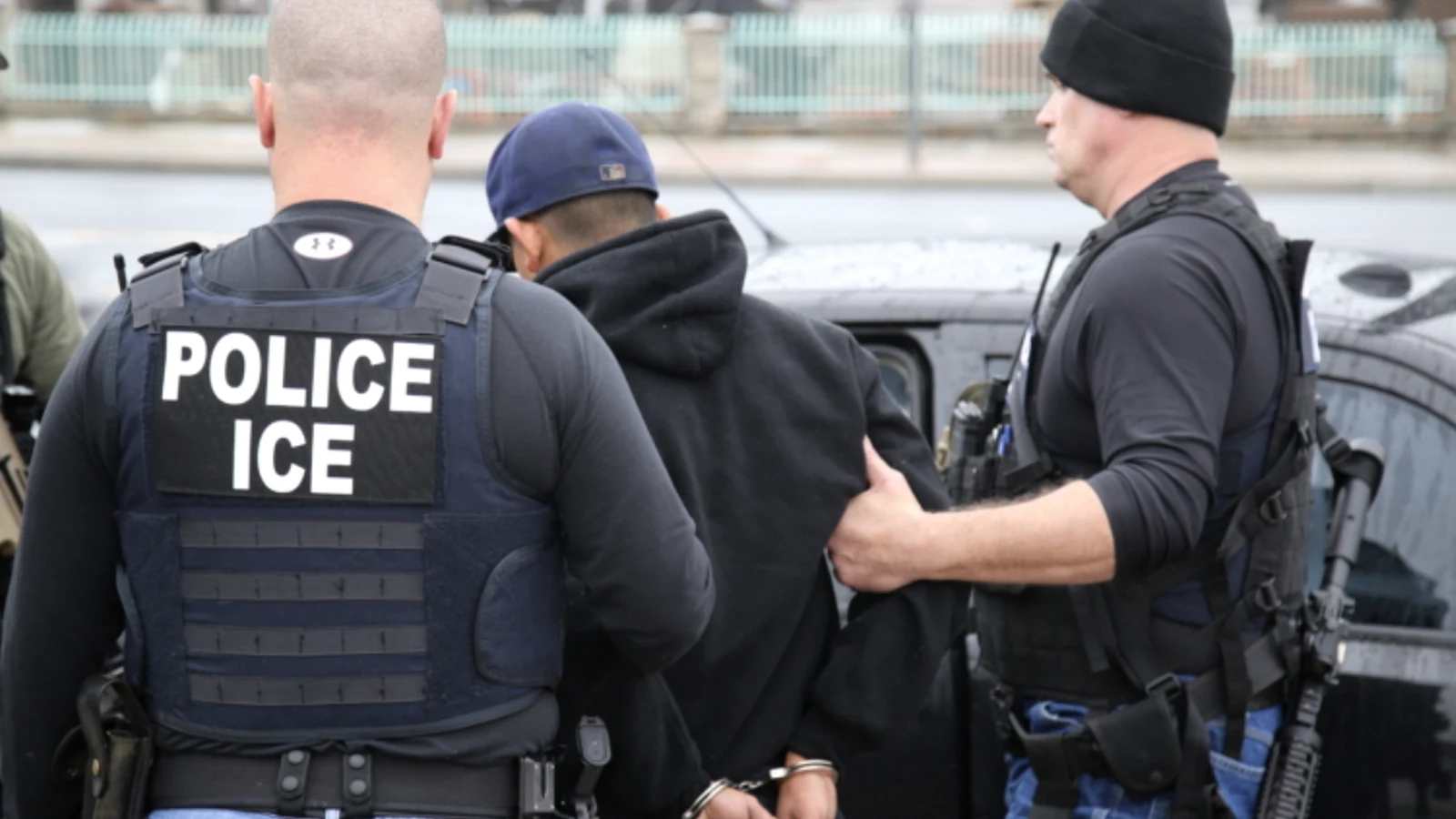 ICE officers detaining a person during an immigration enforcement action.
