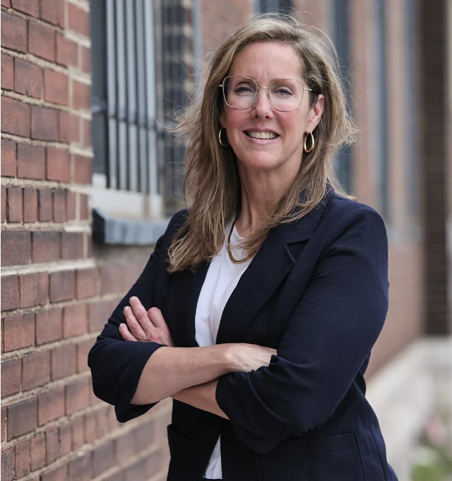 Elizabeth Sparks-Holmes standing near a brick wall.